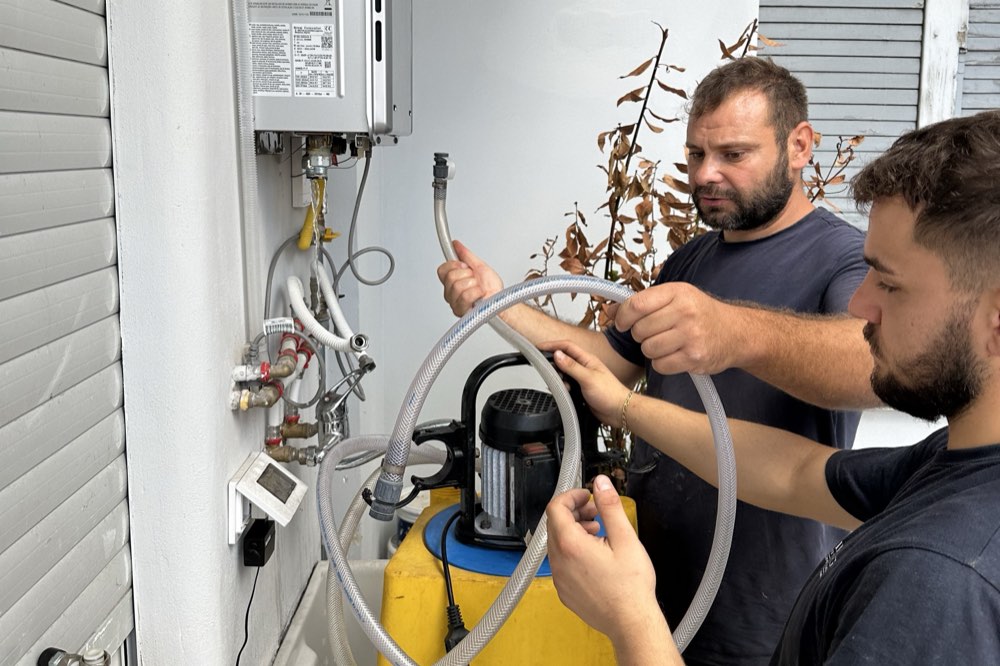 Due tecnici di Romana Interventi al lavoro su uno scaldabagno a gas